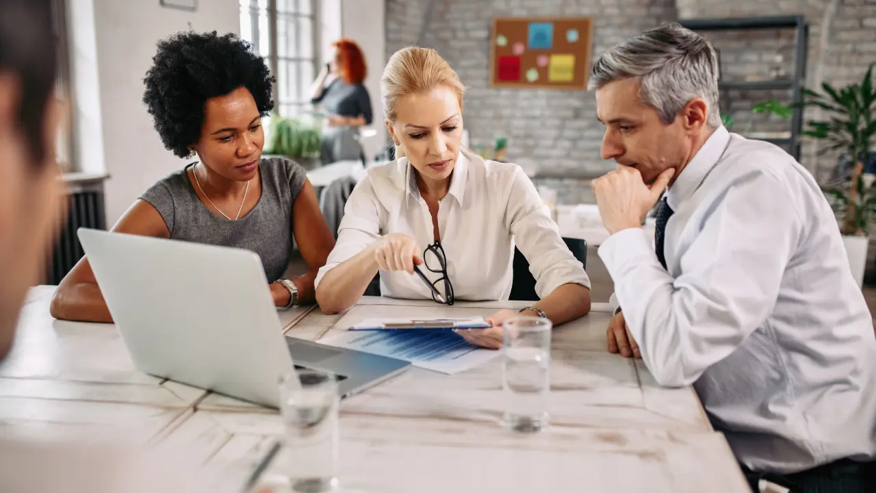 Three colleagues discussing work at a table.
