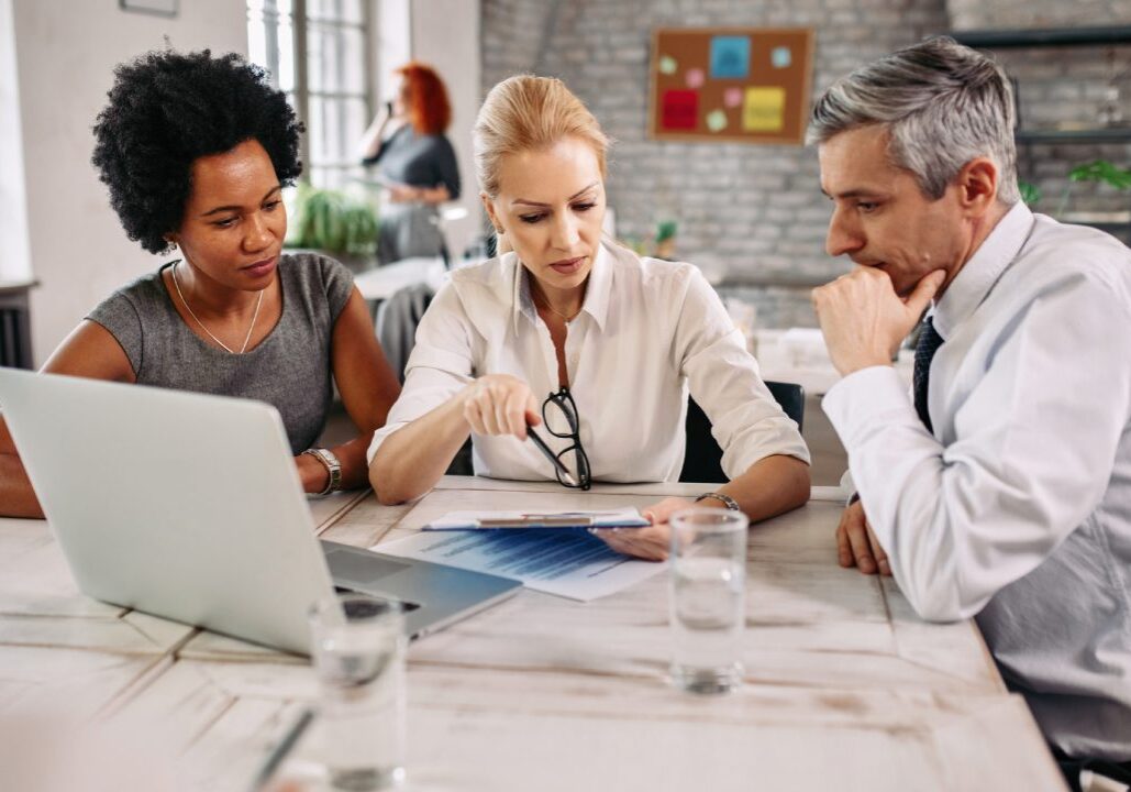 Three colleagues discussing work at a table.